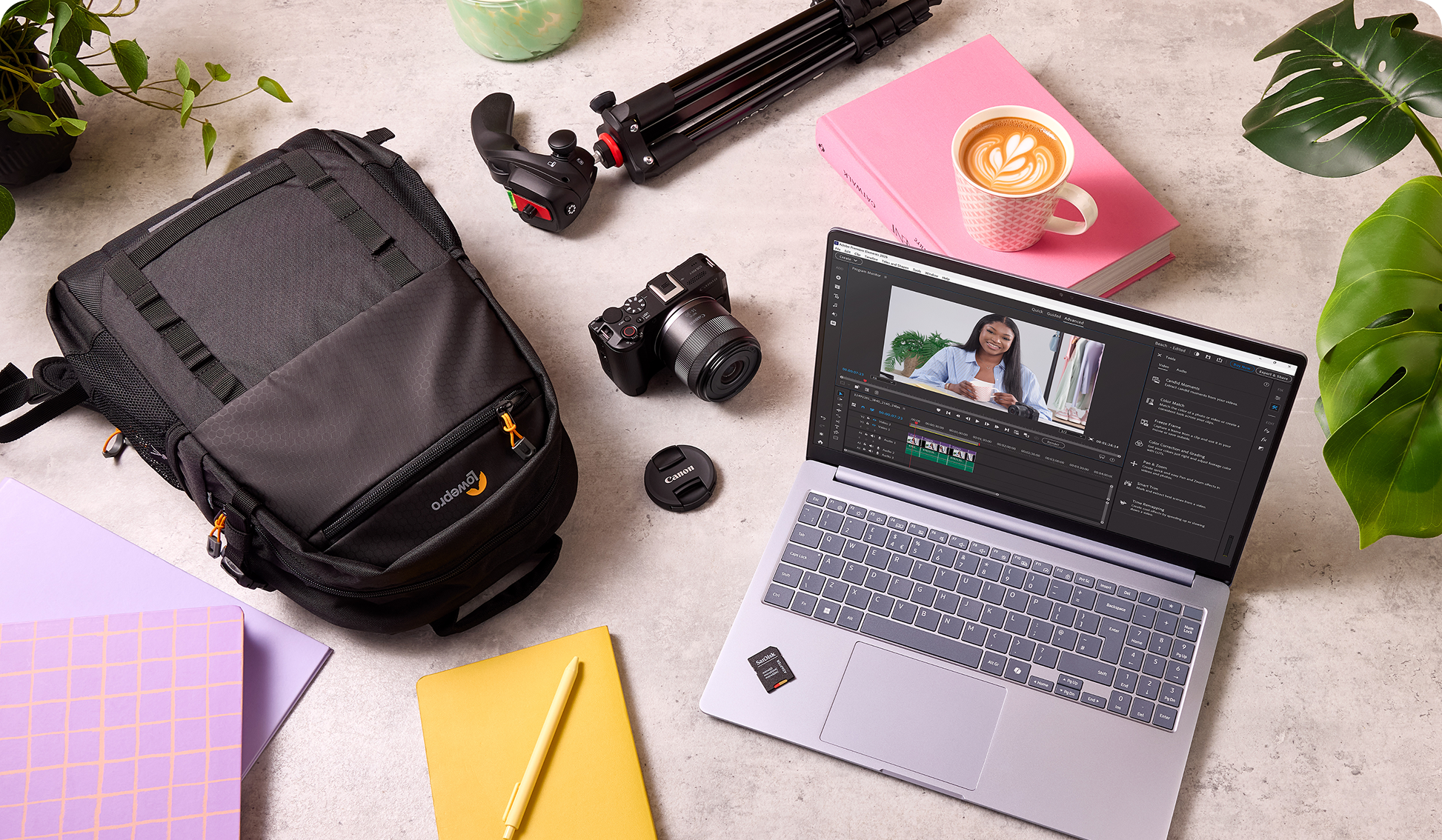 A collection of tech products on a worktop, including a tripod, camera, laptop, SD card and backpack