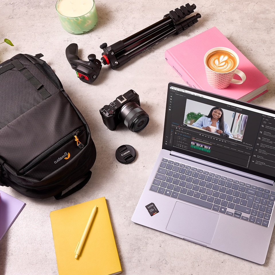 A collection of tech products on a worktop, including a tripod, camera, laptop, SD card and backpack