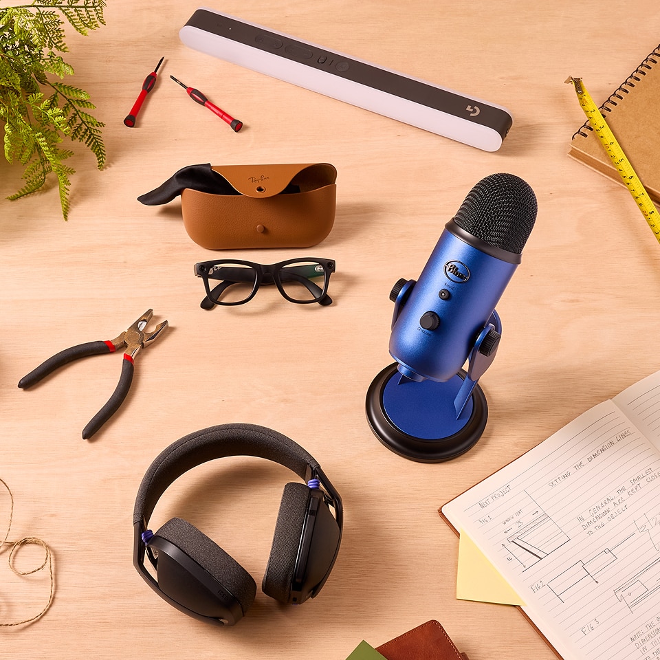A collection of tech products on a worktop, including a microphone, light, smart glasses and a gaming headset