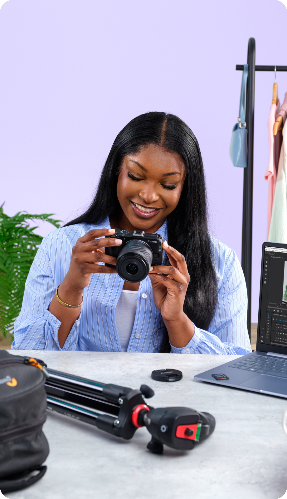 Desola Alafia behind a grey desk with lots of cameras and camera equipment on it